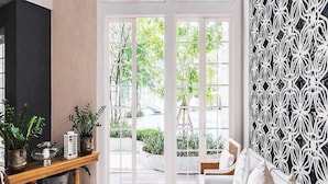 A living room with a white sofa, a wooden console table with plants, and a patterned floor.