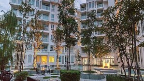 A courtyard with a pool, outdoor seating, and a multi-story building in the background.