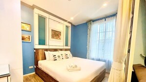 A bedroom with a wooden bed, a white duvet, and a set of towels.