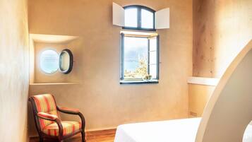 Un dormitorio con una cama grande, una ventana con vistas, una silla y un espejo fijado a la pared.