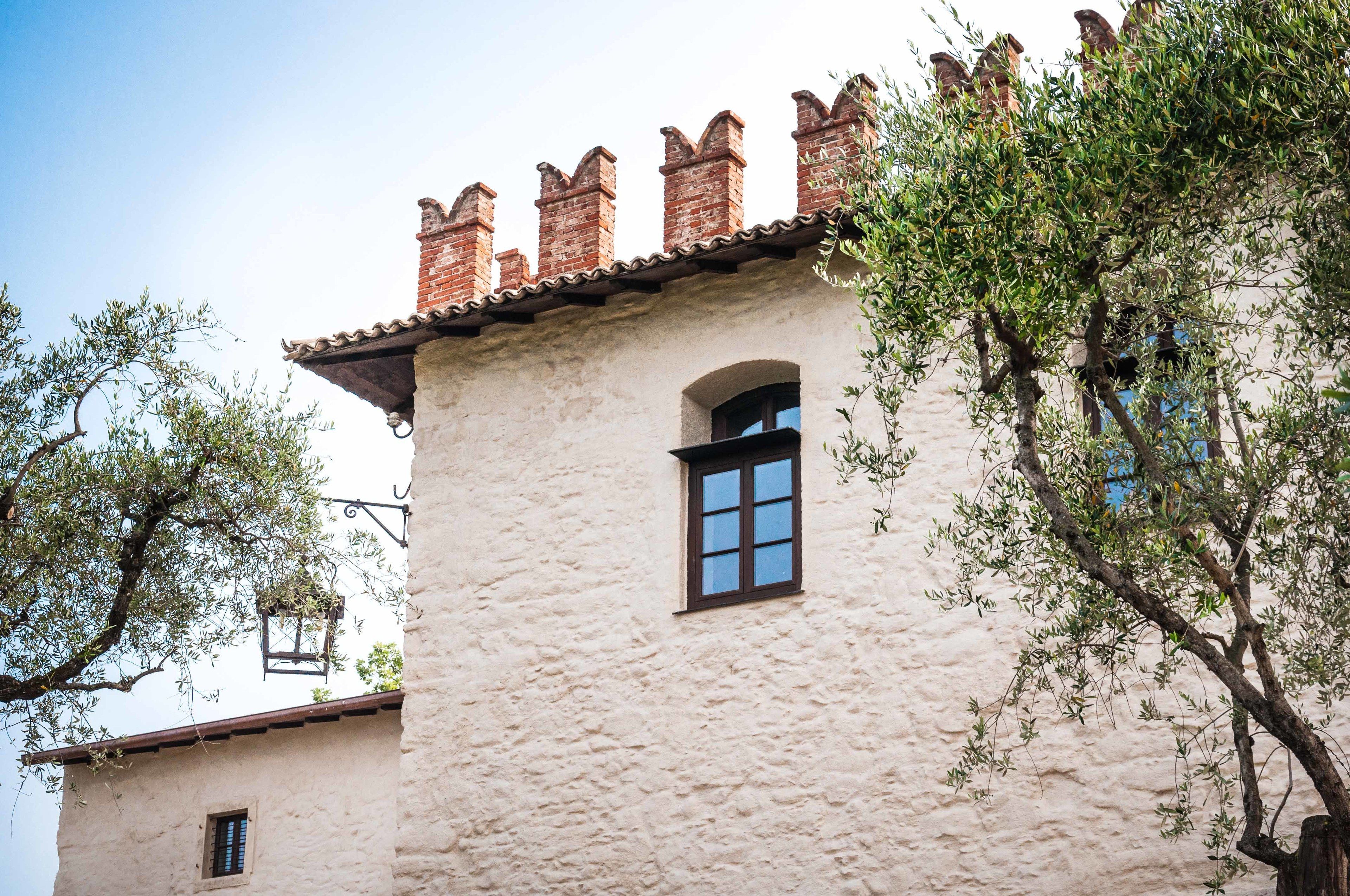 A building with a textured facade, a small window, and a tiled roof.