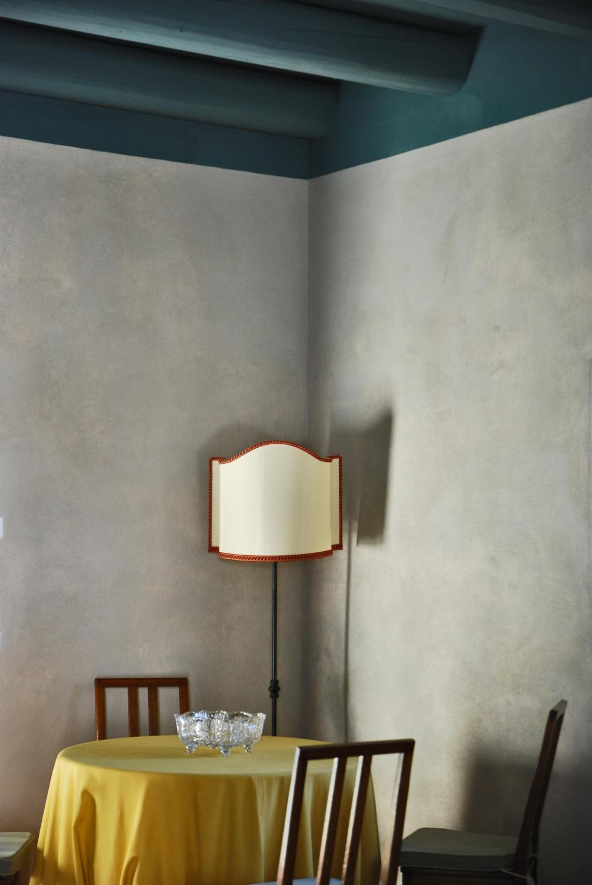Un área de comedor con una mesa dispuesta para dos personas, una lámpara y una silla.