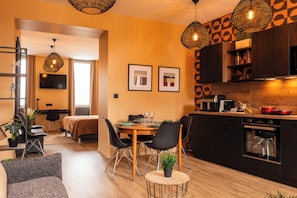 A modern kitchen with a dining area, wooden flooring, and pendant lighting.