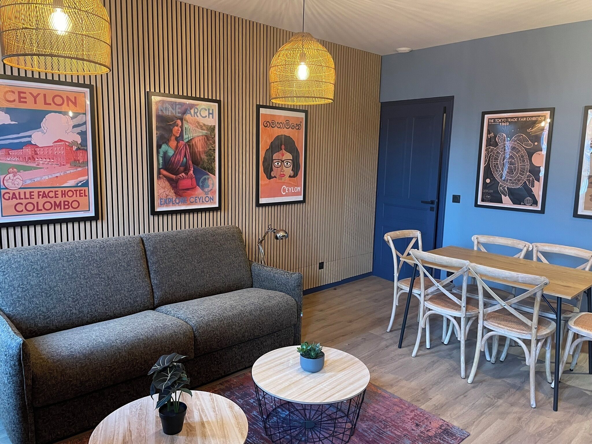 Ein moderner Loungebereich mit einer Couch, einem runden Couchtisch mit Pflanze und einem Esstisch-Set.