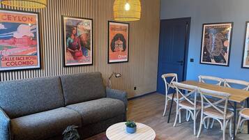 Ein moderner Loungebereich mit einer Couch, einem runden Couchtisch mit Pflanze und einem Esstisch-Set.
