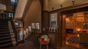 A spacious lobby with a staircase, a bar area, and a seating area with a patterned rug. - Nouvel Hôtel & Appartements (Oyonnax)