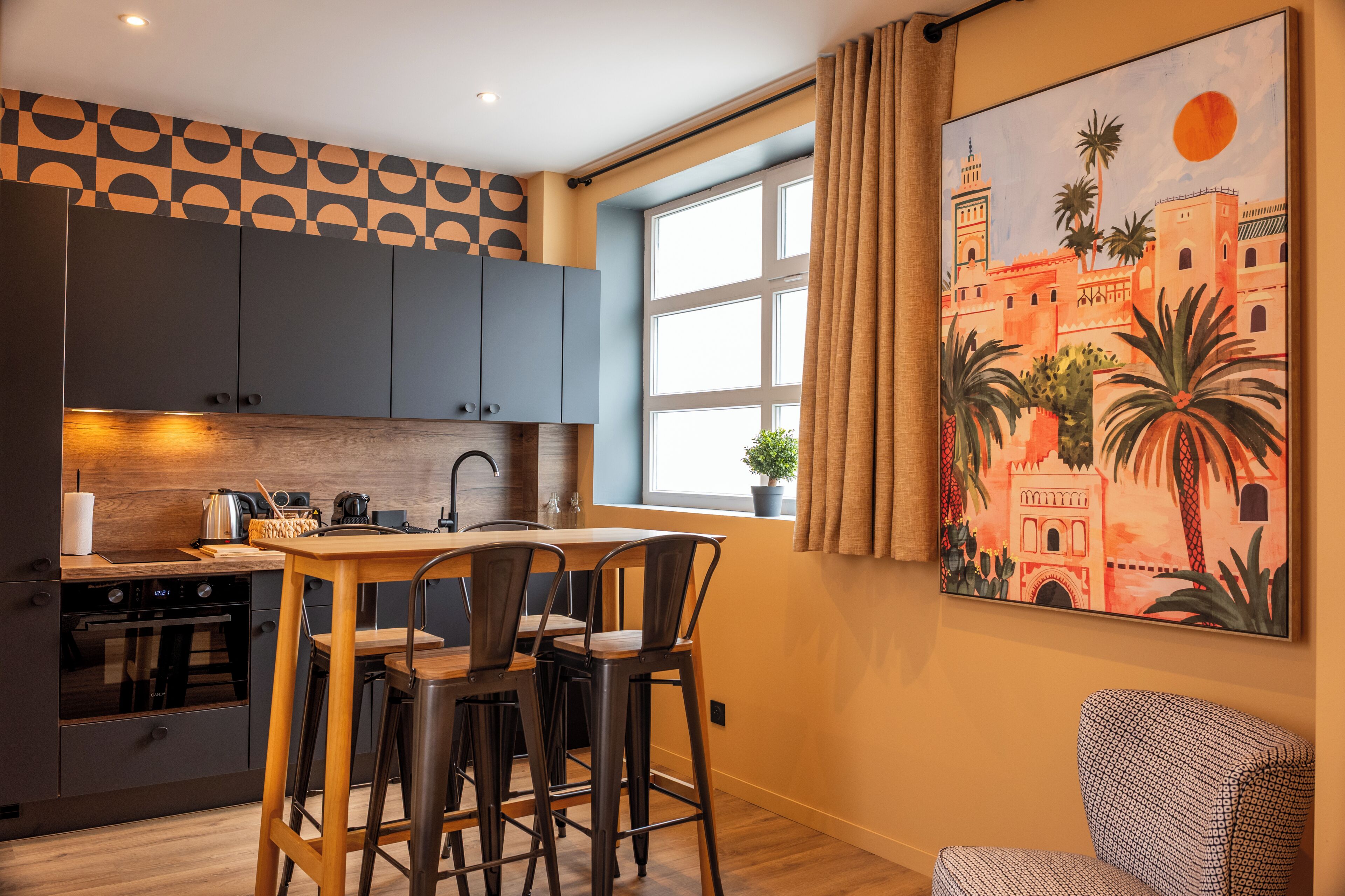A modern kitchen with dark cabinets, a wooden table, and bar stools.