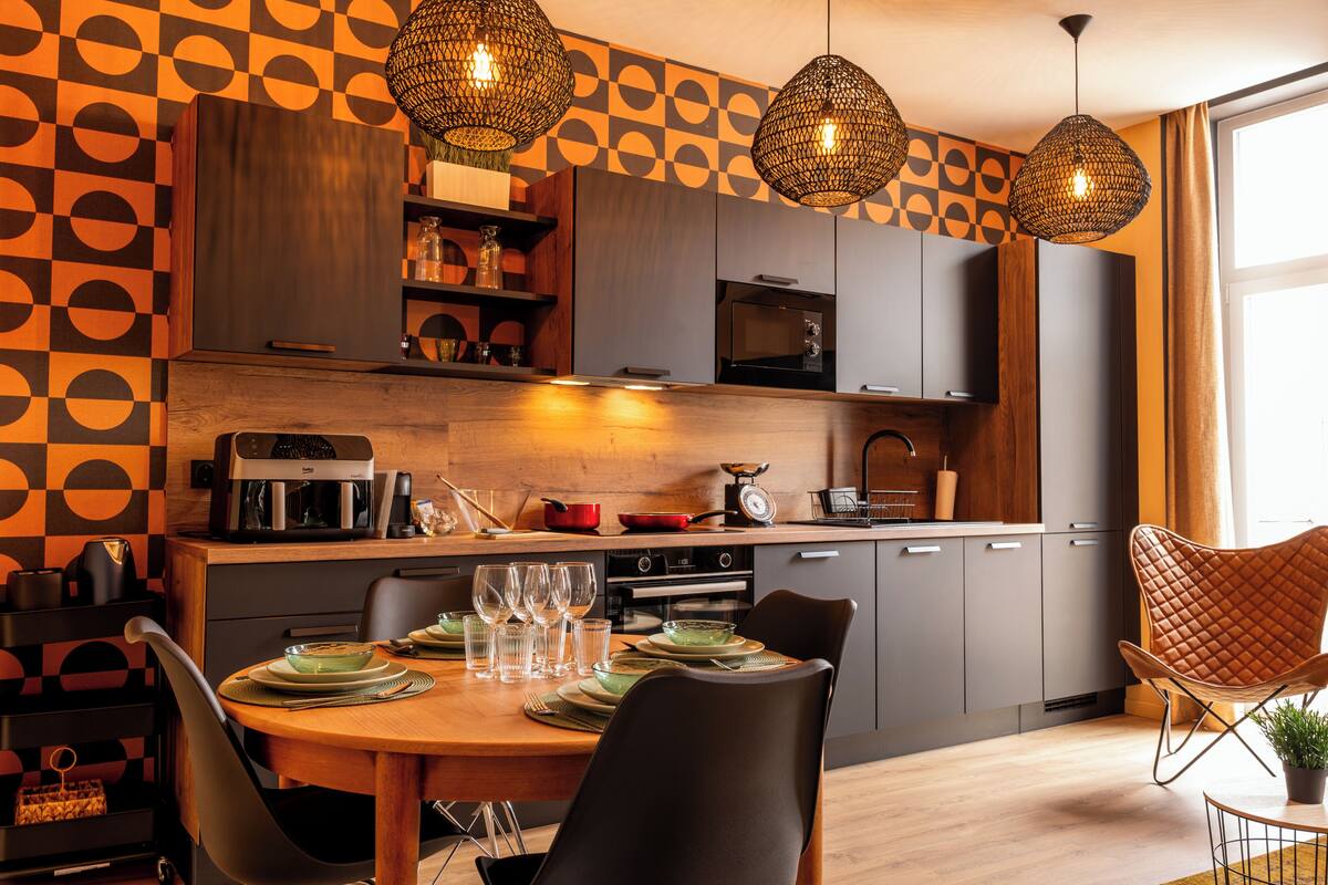 Una cocina moderna con comedor, que incluye una mesa de madera, sillas y lámparas colgantes.
