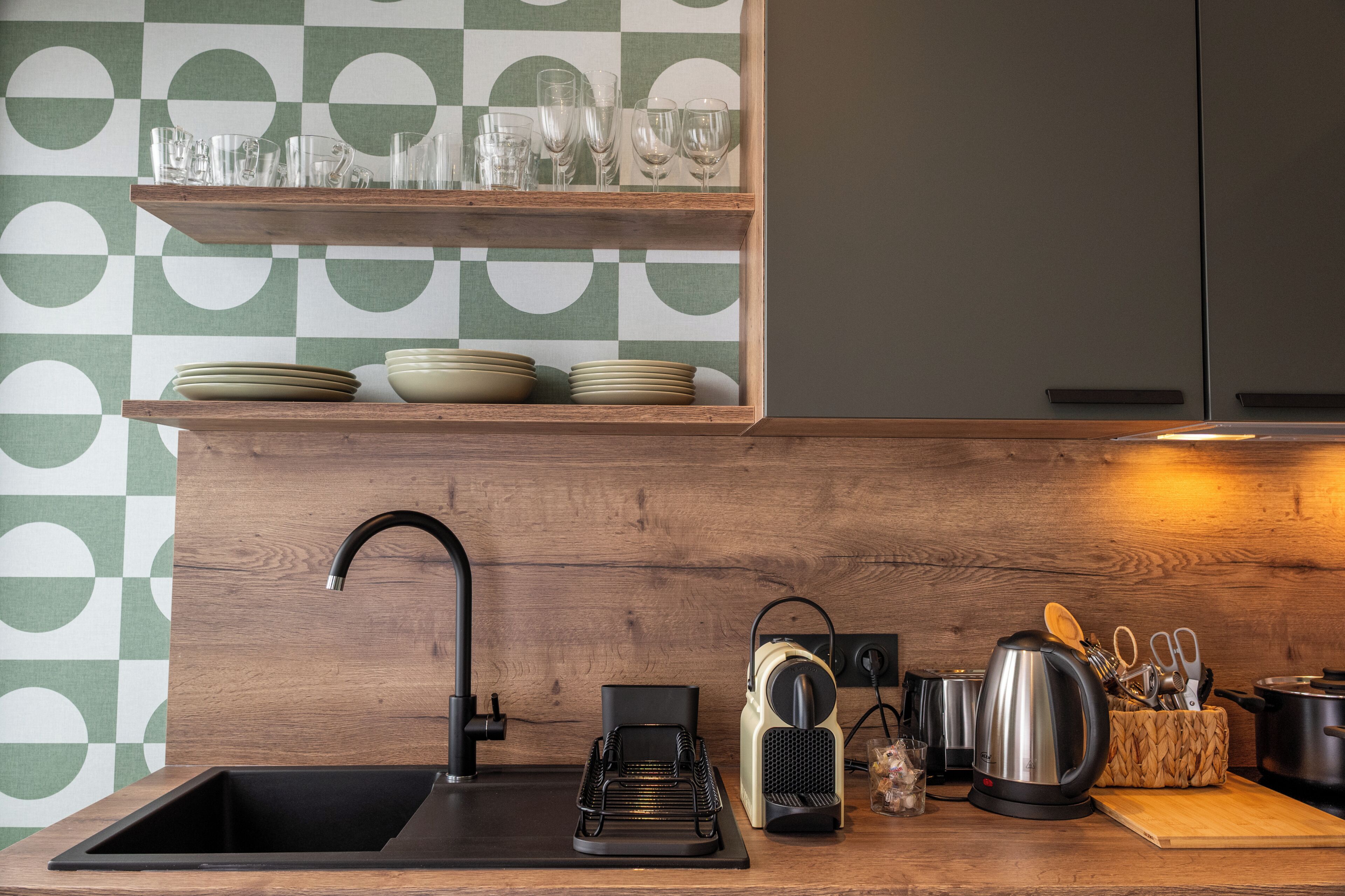 Una cocina de diseño moderno, con encimera de madera, pileta negra y cafetera.