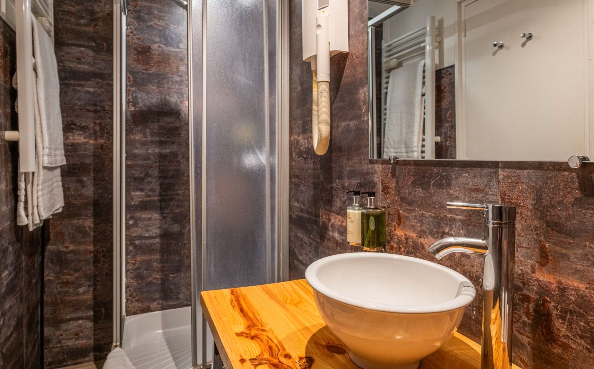 Une salle de bain moderne avec une douche à parois de verre, un meuble-lavabo en bois et un miroir au-dessus du meuble.