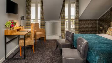 A compact hotel room with a bed, a desk, a chair, and a TV.