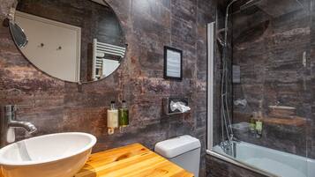 Un baño moderno con un lavabo grande, espejo y ducha.