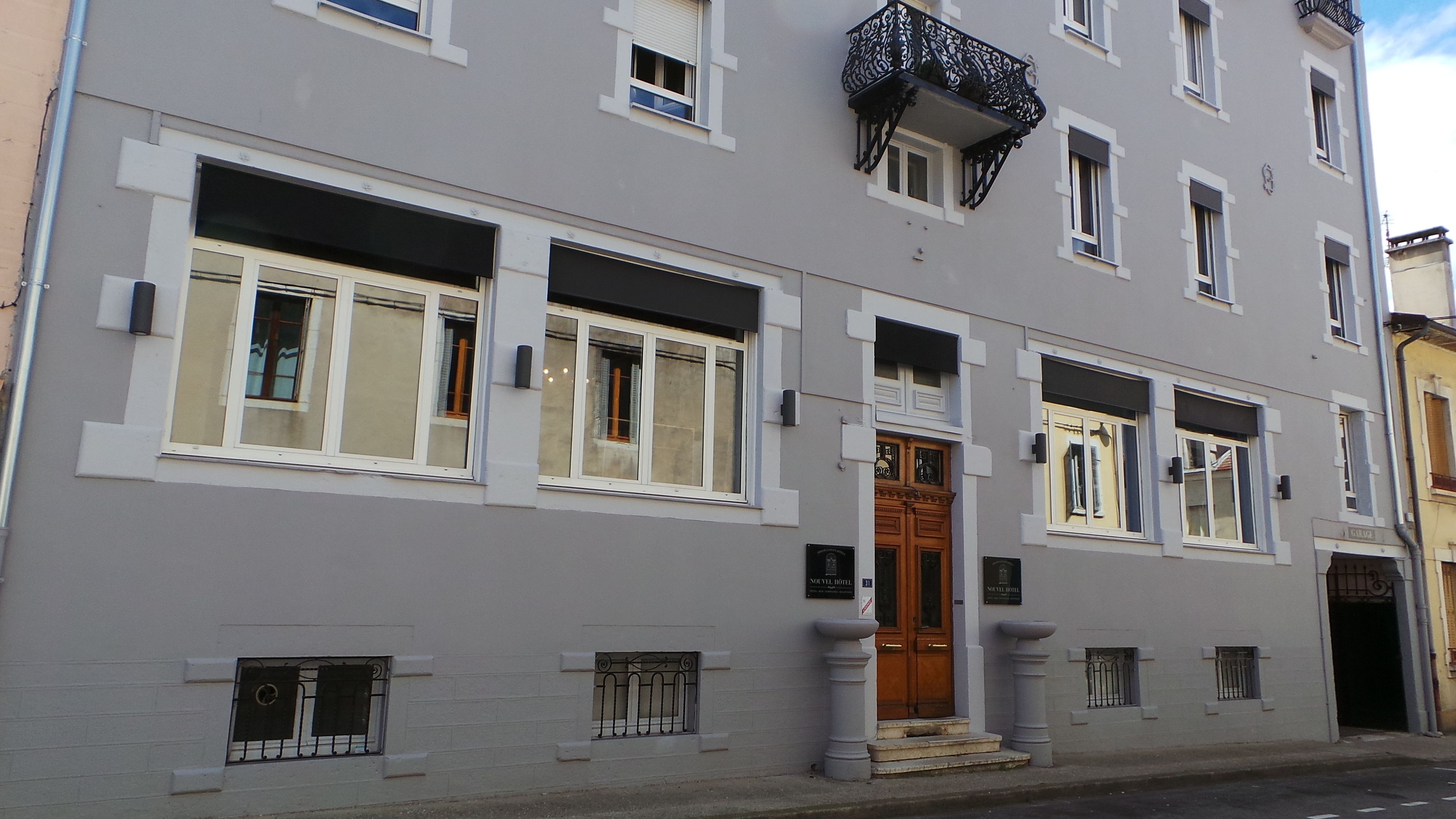 A multi-story building with a prominent entrance, large windows, and a balcony with ornate railings.