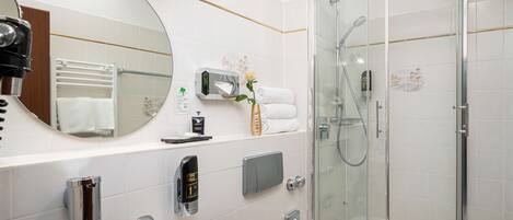A modern bathroom with a glass-enclosed shower, a sink with a mirror, and a towel rack.