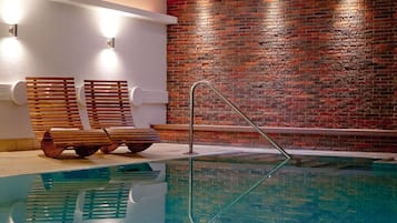 Una piscina techada, sillones reclinables de piscina