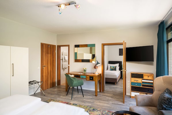 A hotel room with a bed, desk, chair, dresser, and a TV. - Arthotel ANA GOLD (Augsburg)