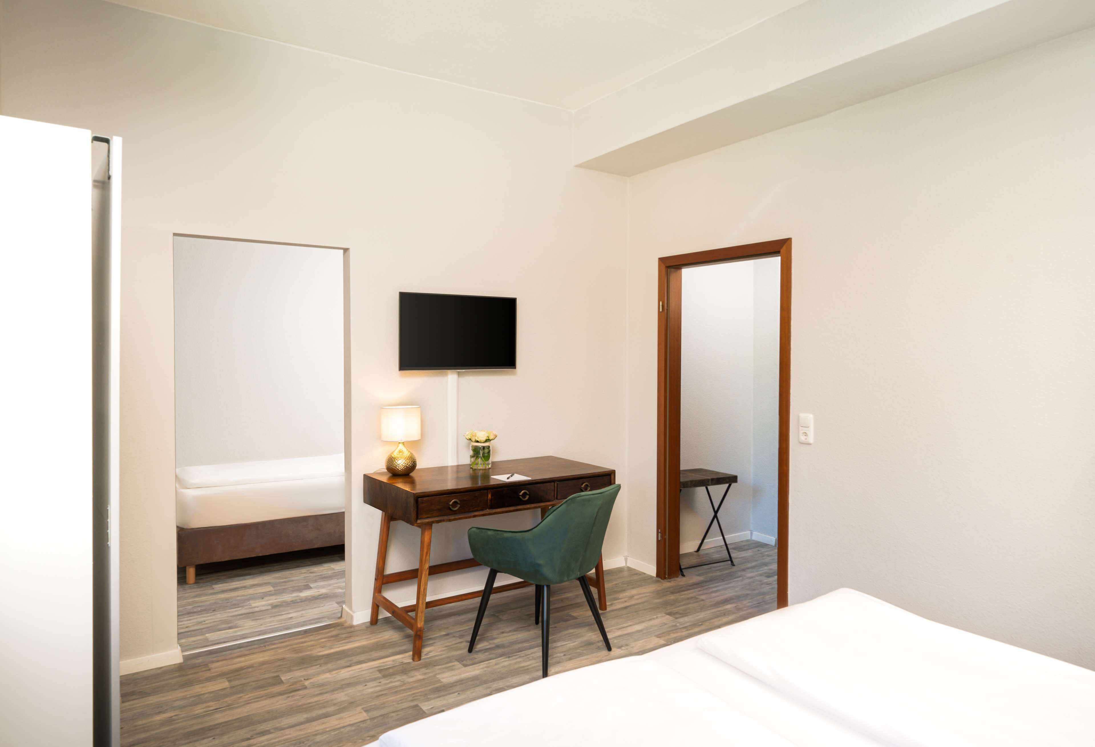 Een hotelkamer met een bed, een bureau met stoel, een televisie en een spiegel.