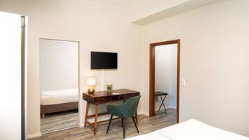 Een hotelkamer met een bed, een bureau met stoel, een televisie en een spiegel.