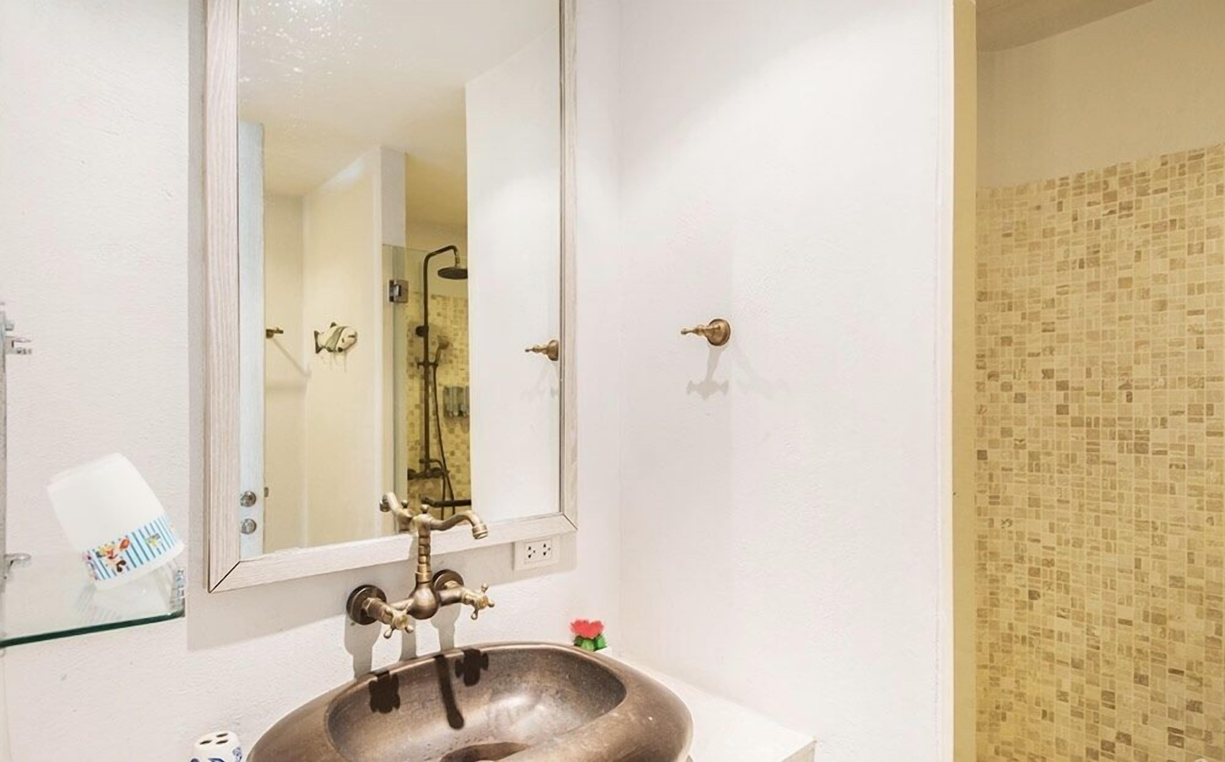 A bathroom with a white sink, a mirror, and a shower.