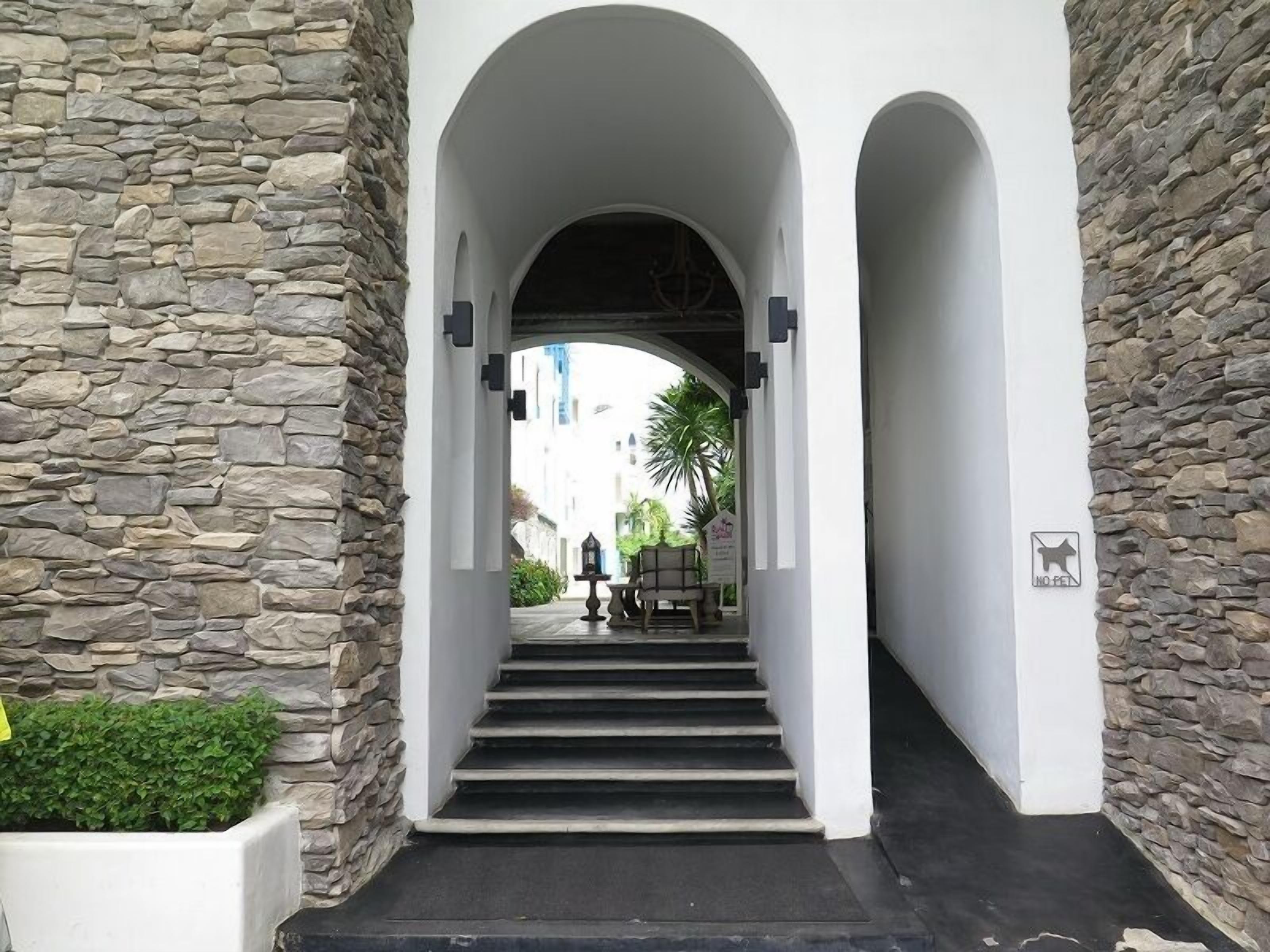 A stone-walled entrance with a staircase leading to a covered area.