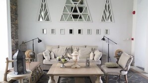 A living room with a stone-patterned floor, a beige sofa, a coffee table with decorative items, and a stone wall with geometric window designs. - Chelona Huahin Condo Garden View by Dome (Hua Hin)