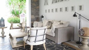 A cozy living area with a stone floor, a white sofa, a wicker side table, and a decorative lamp. - Chelona Huahin Condo Garden View by Dome (Hua Hin)