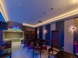 A modern interior with a bar area, seating, and a television.