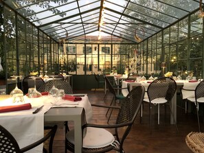 A restaurant with glass walls, tables set with white tablecloths, and chairs. - La Cantina Relais - Fattoria Il Cipresso (Arezzo)