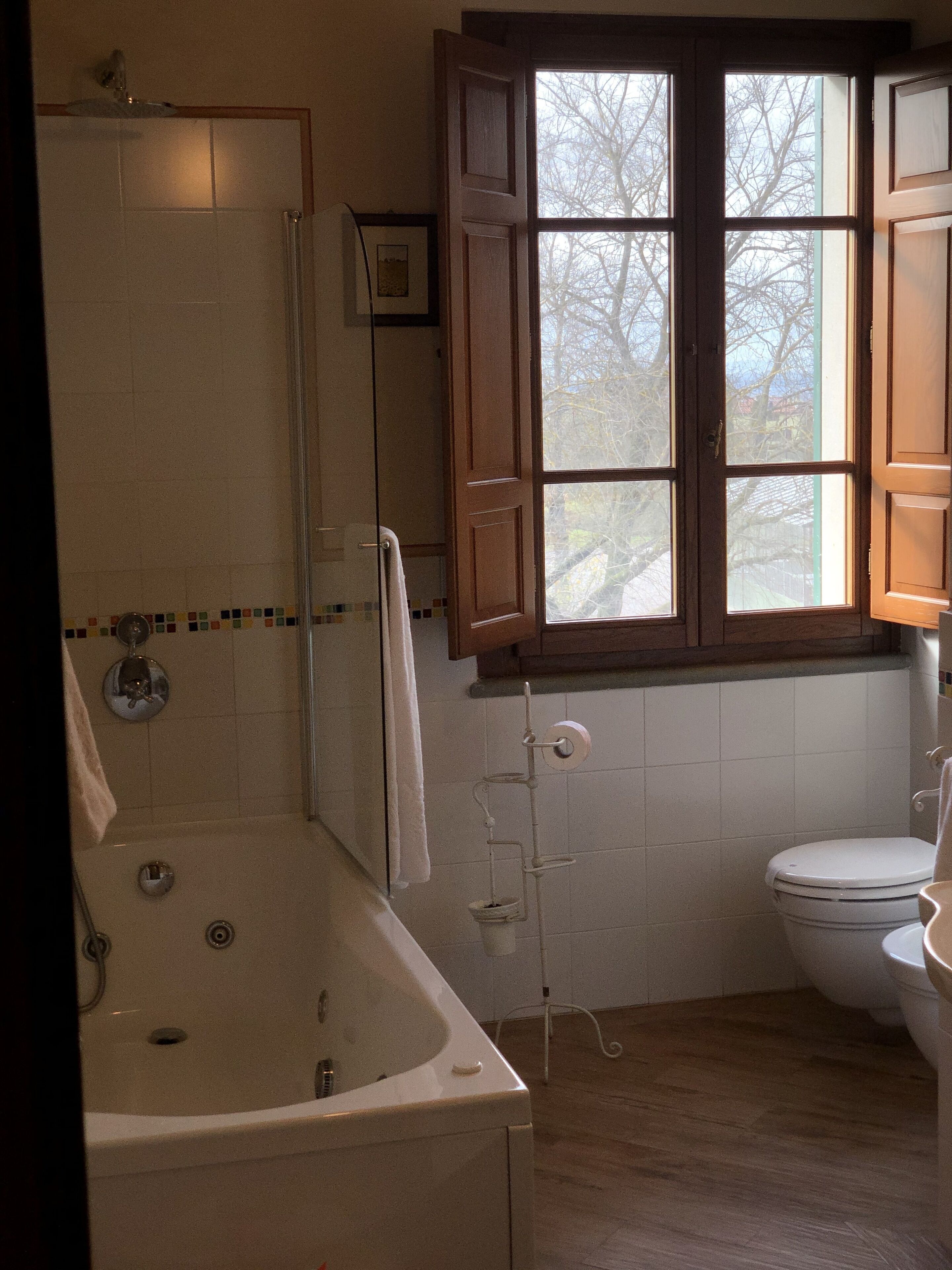 A bathroom with a bathtub, toilet, and a window with a view of trees.