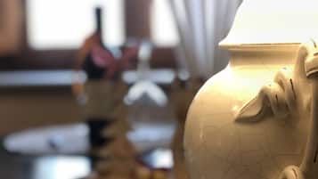 Un primo piano di una lampada in ceramica bianca dalla superficie strutturata, posata su un tavolo con un sottotavolo all'uncinetto.