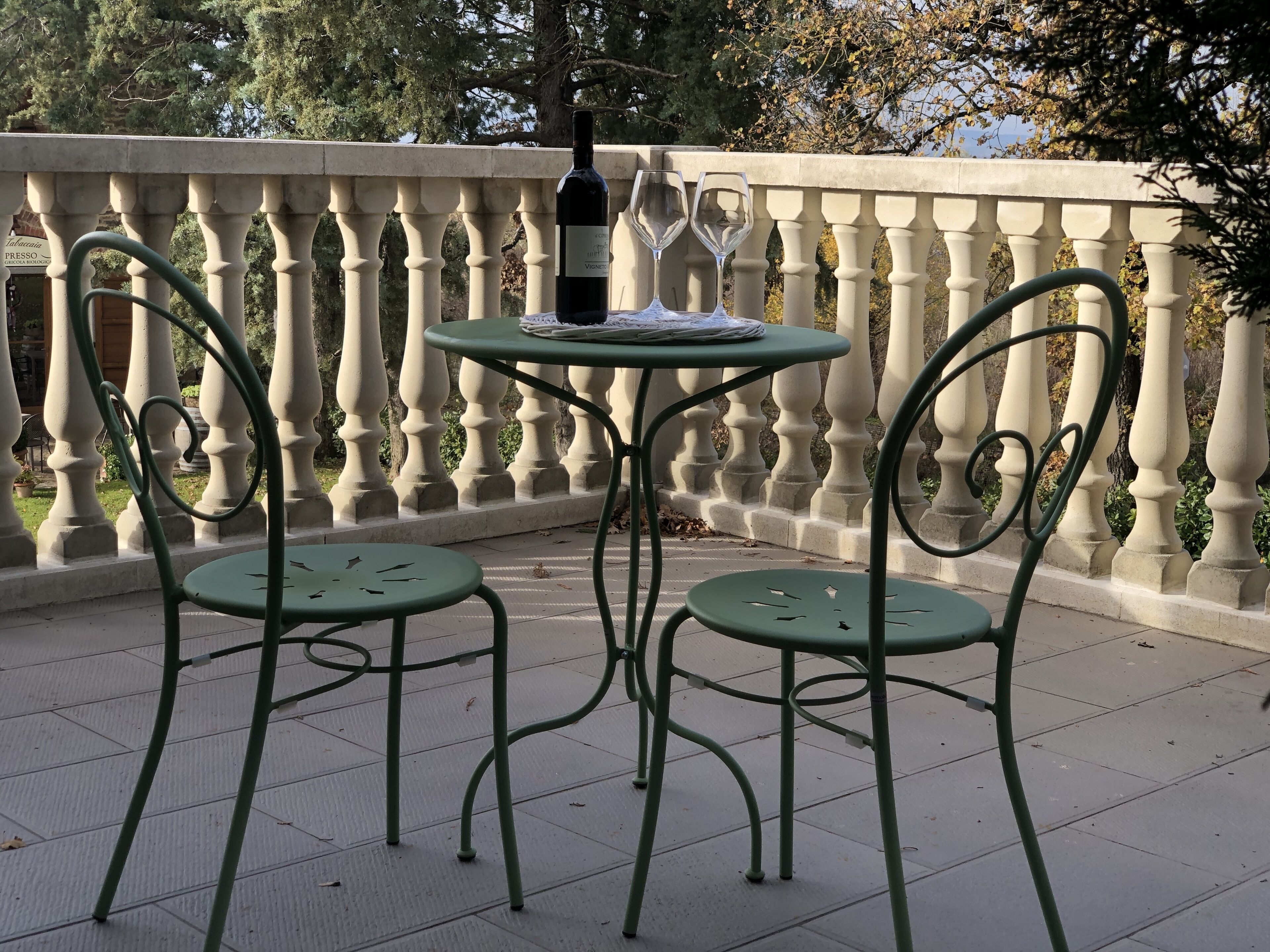 Eine Terrasse mit Tisch und zwei Stühlen, einer Weinflasche und einer Speisekarte.