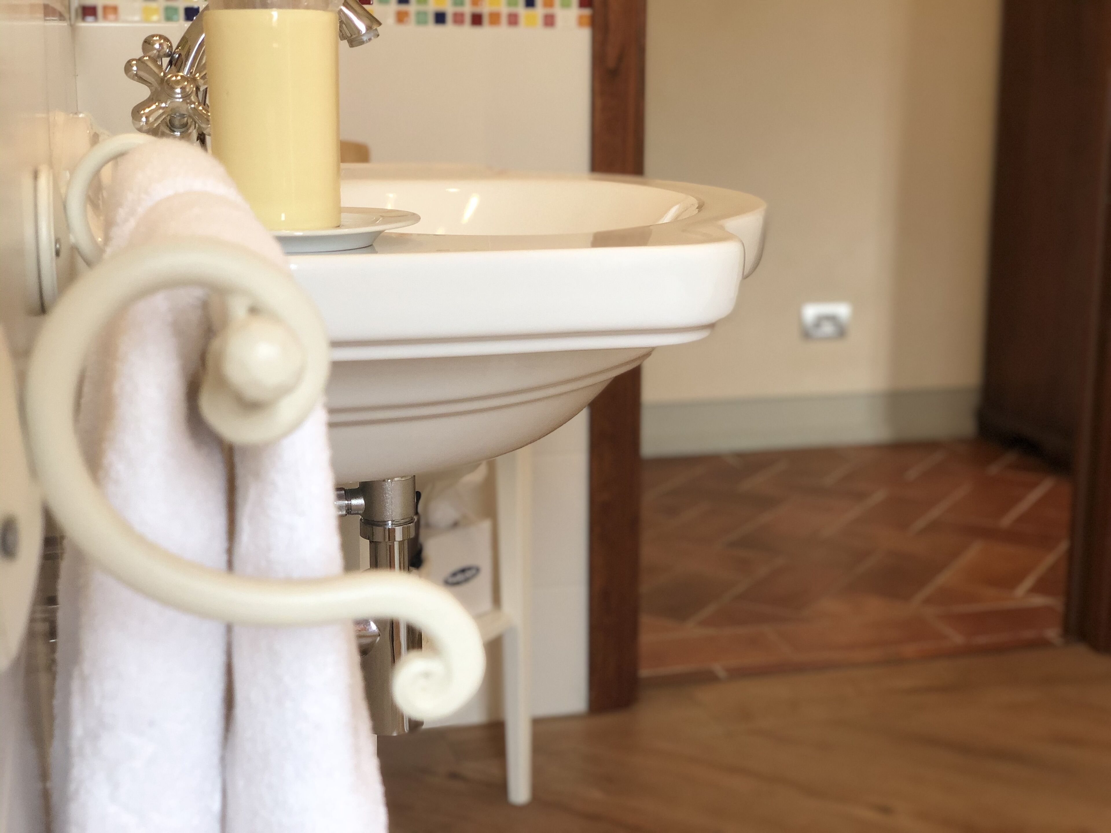 A bathroom with a white sink, a towel rack, and a wooden floor.