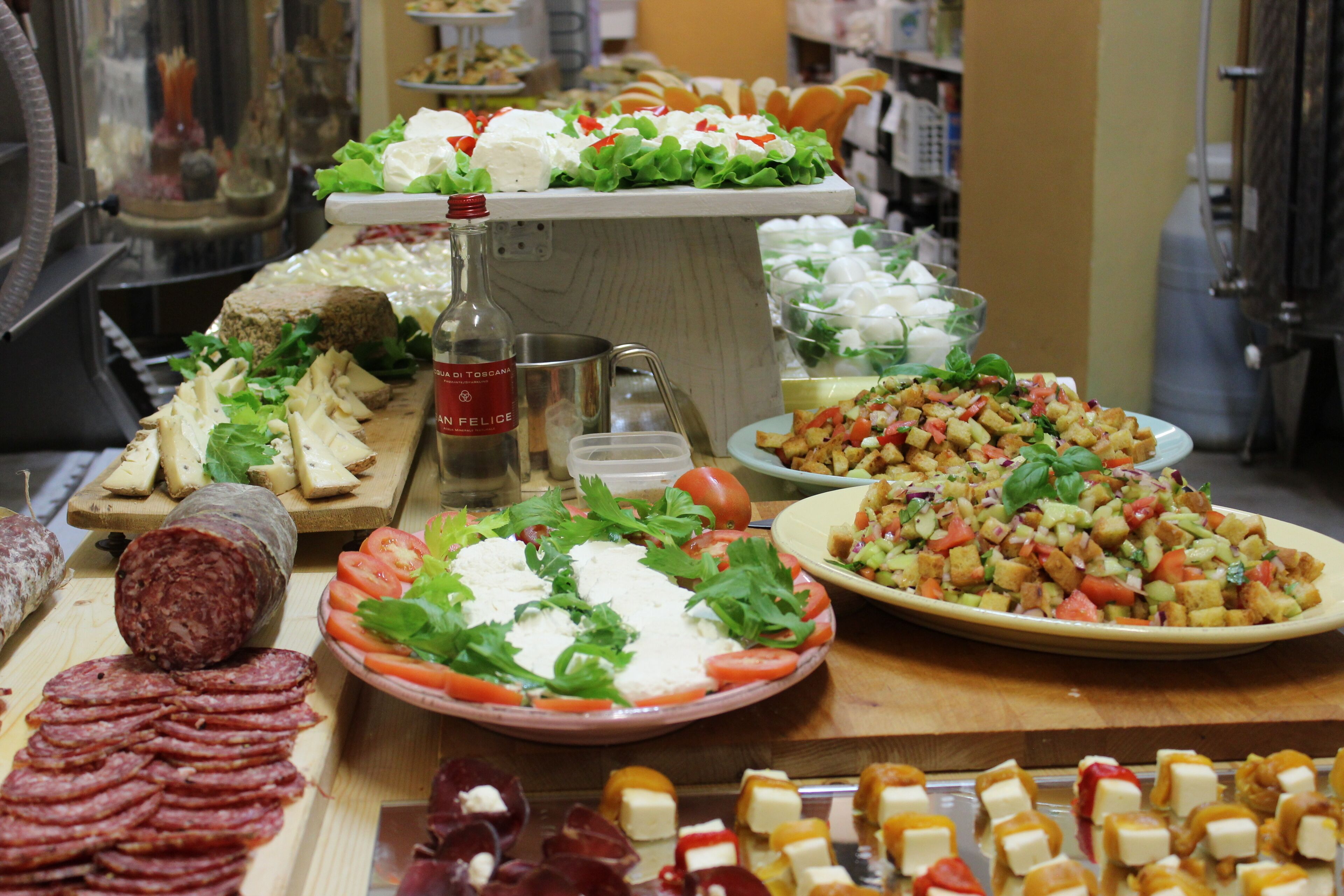 Buffet amb diverses opcions gastronòmiques, com ara làmines de carn, formatges, amanides i una ampolla de salsa.