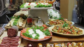 Buffet amb diverses opcions gastronòmiques, com ara làmines de carn, formatges, amanides i una ampolla de salsa.