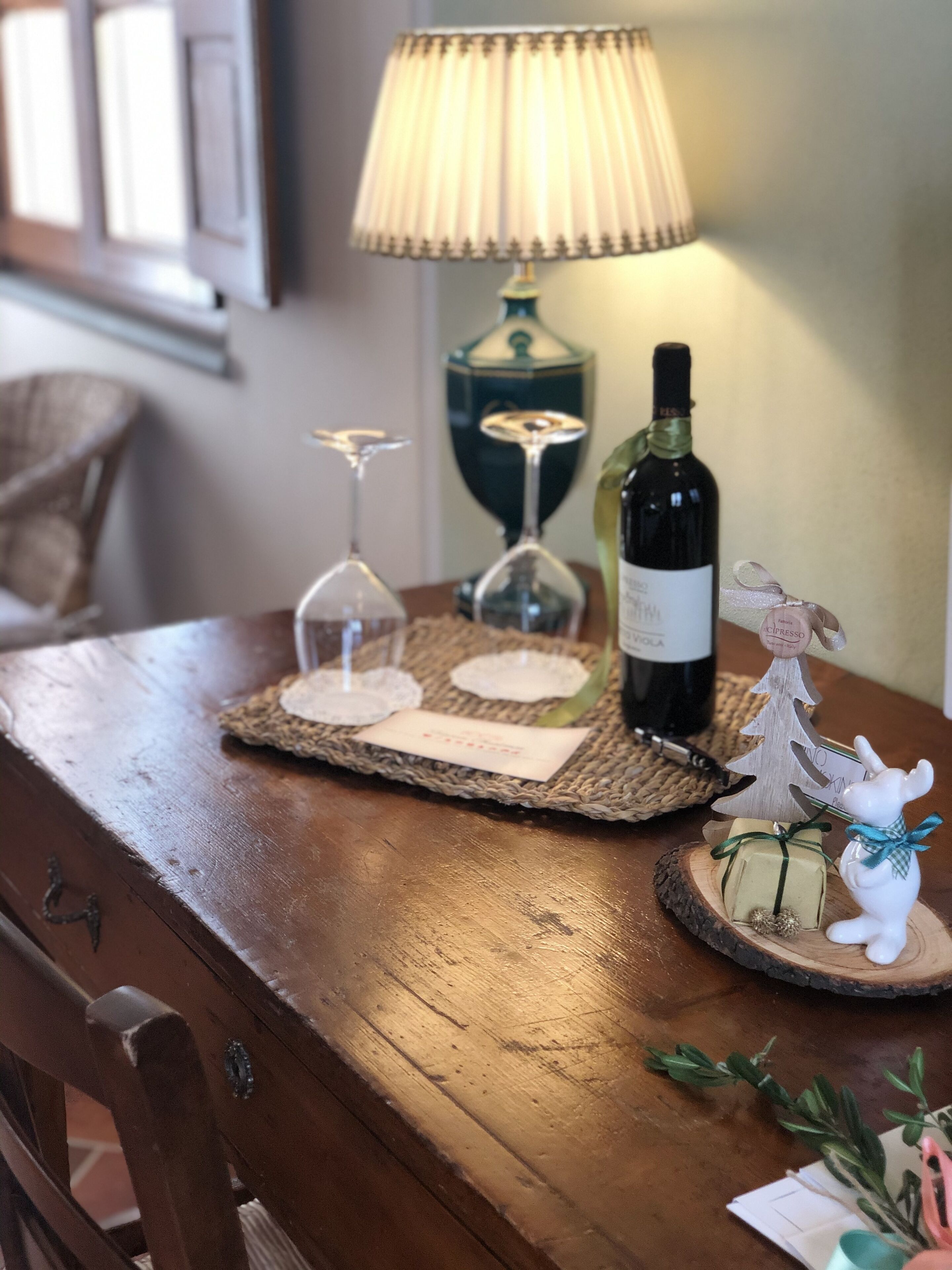 Ein Holztisch mit einer Weinflasche, zwei Weingläsern und einer kleinen Weihnachtsbaumdeko.