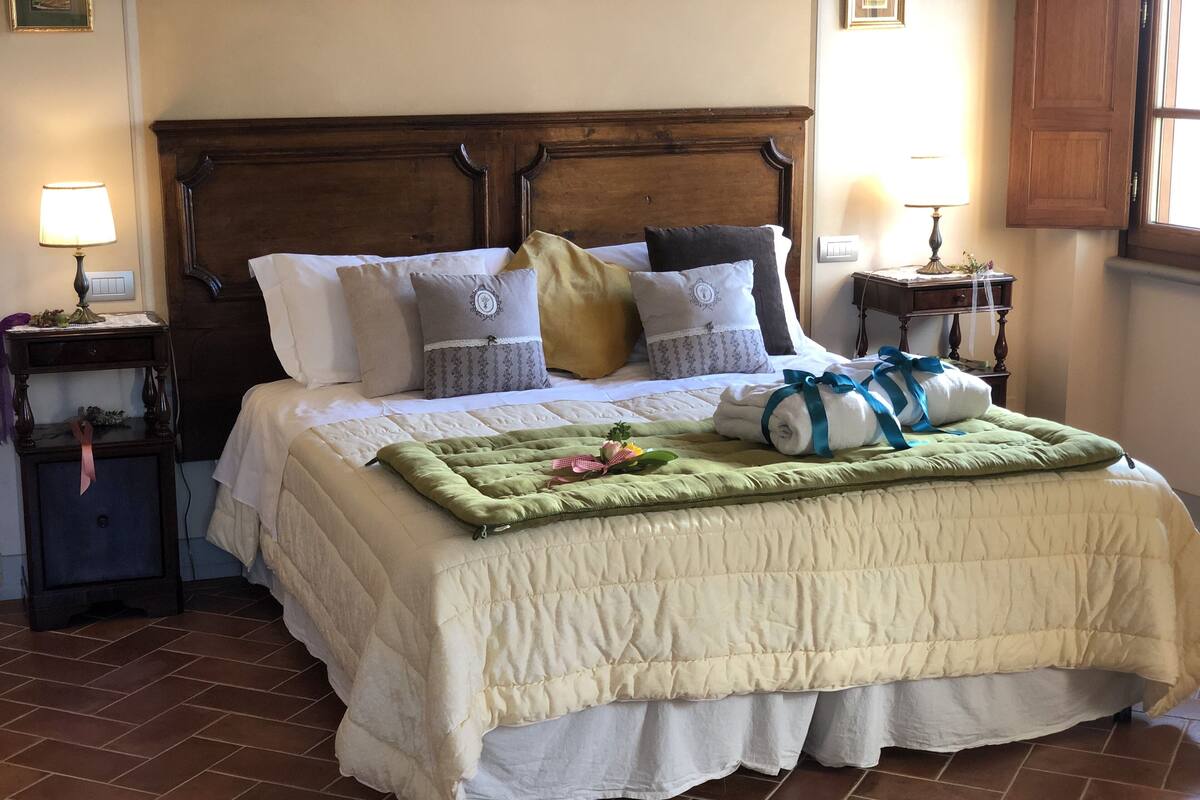 A neatly made bed with a quilted bedspread, multiple pillows, and a green throw blanket.