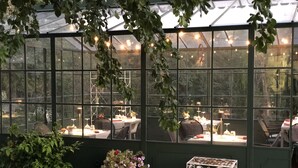 A greenhouse-style dining area with tables and chairs, surrounded by greenery and string lights. - La Cantina Relais - Fattoria Il Cipresso (Arezzo)