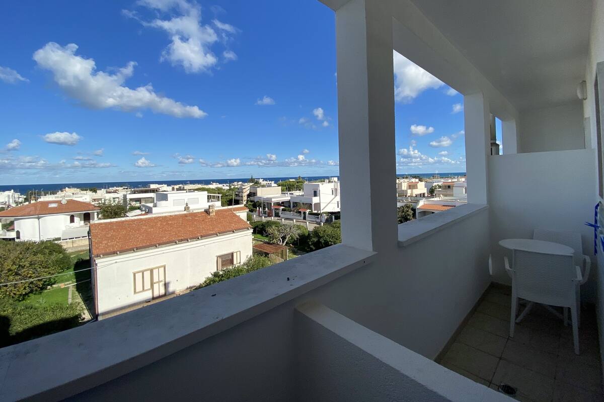 A balcony with a view of a cityscape and the sea.