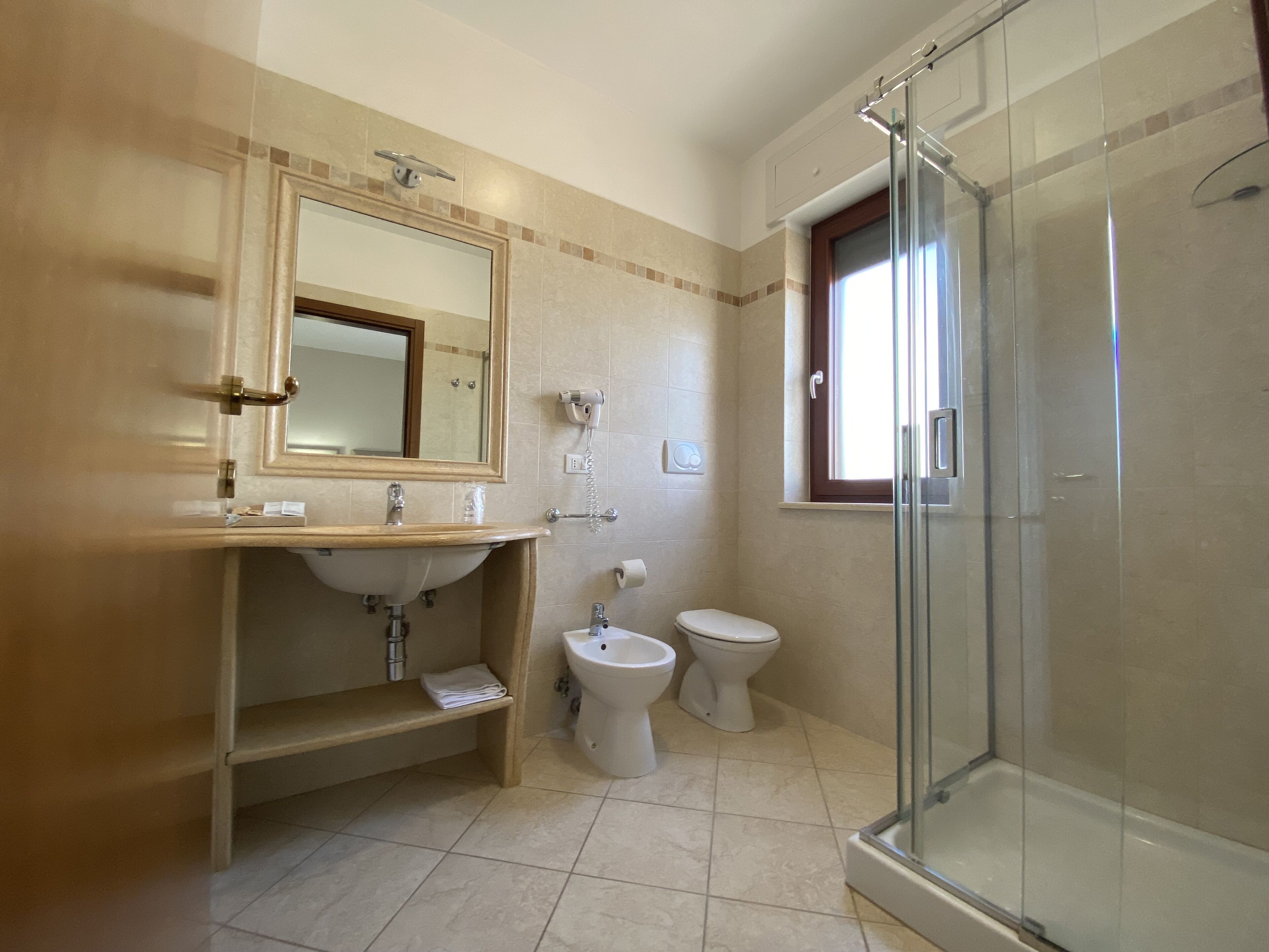 Un baño moderno con cabina de ducha de vidrio, un lavabo con espejo, inodoro y bidé.