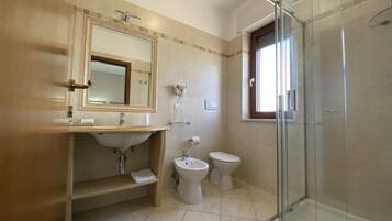 Un baño moderno con cabina de ducha de vidrio, un lavabo con espejo, inodoro y bidé.