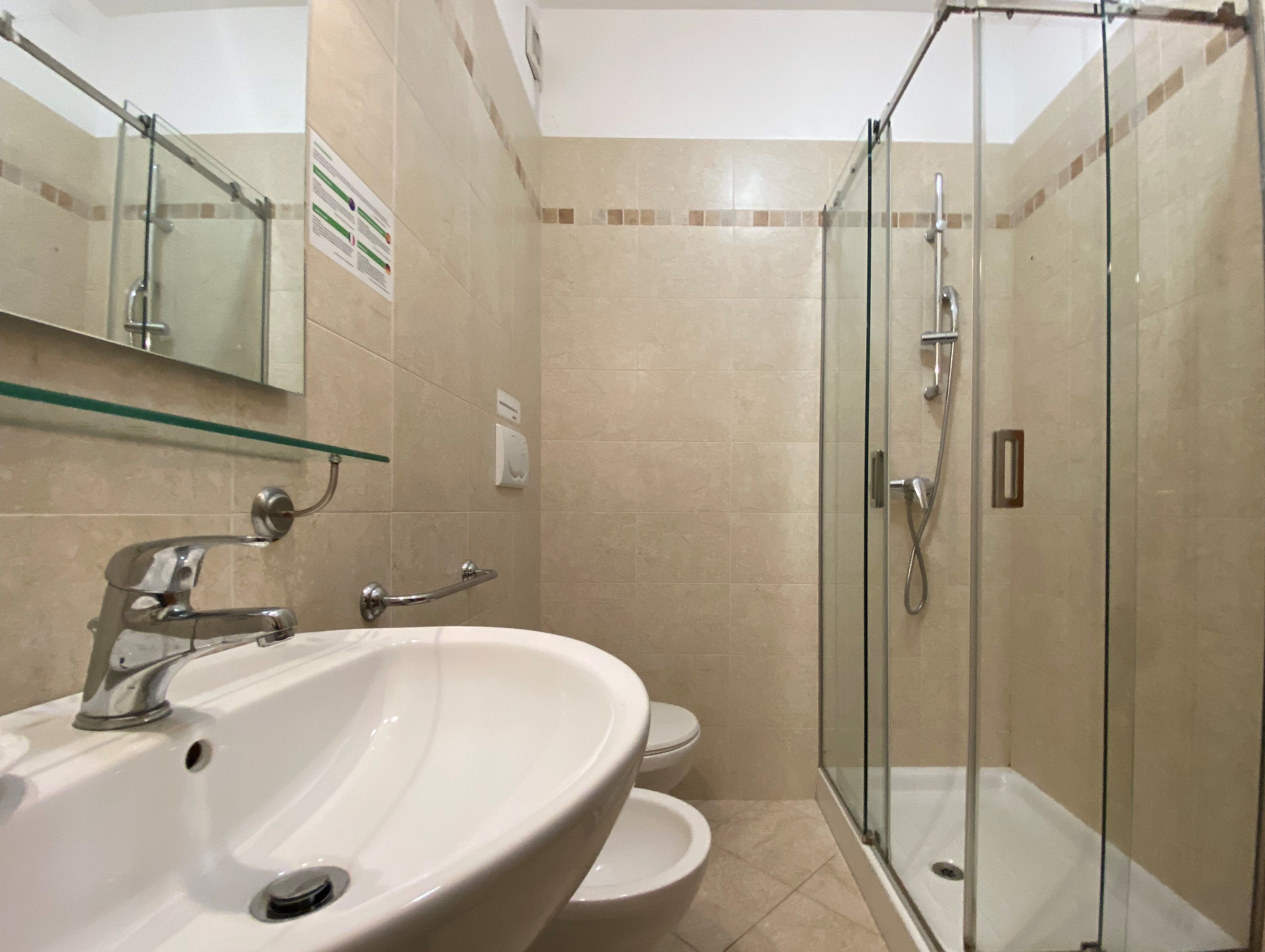 Un baño con ducha de vidrio, lavamanos e inodoro.