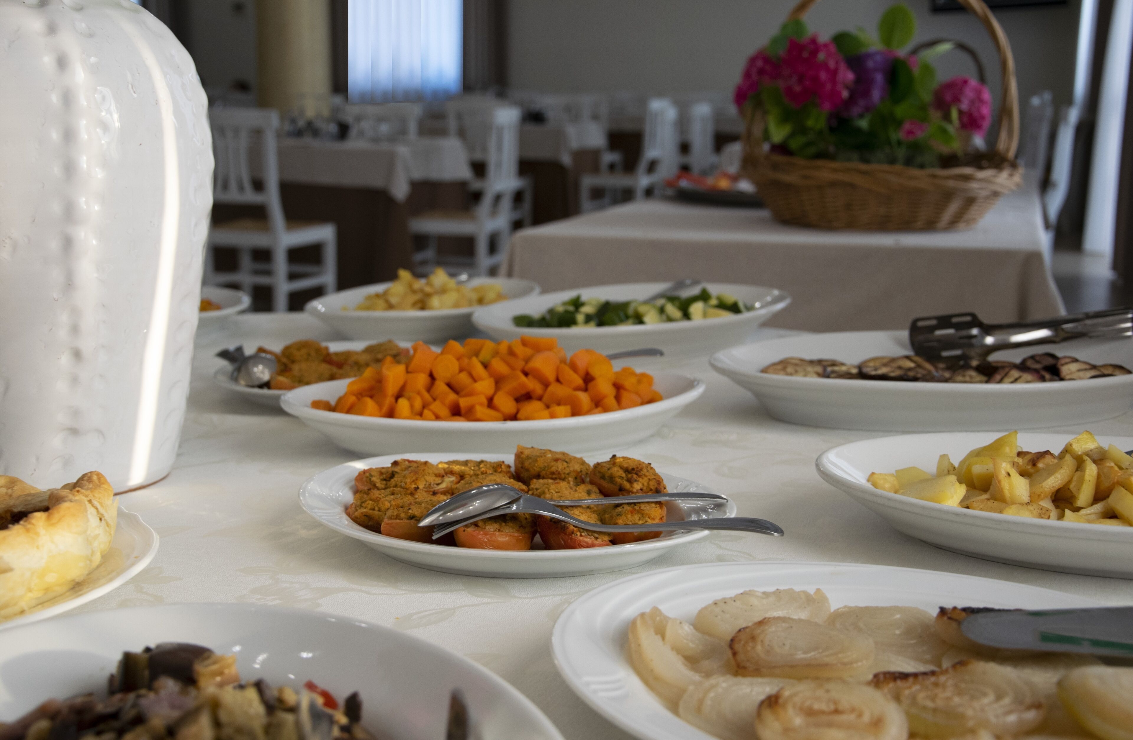 A buffet table with various dishes including roasted potatoes, carrots, and meatballs.