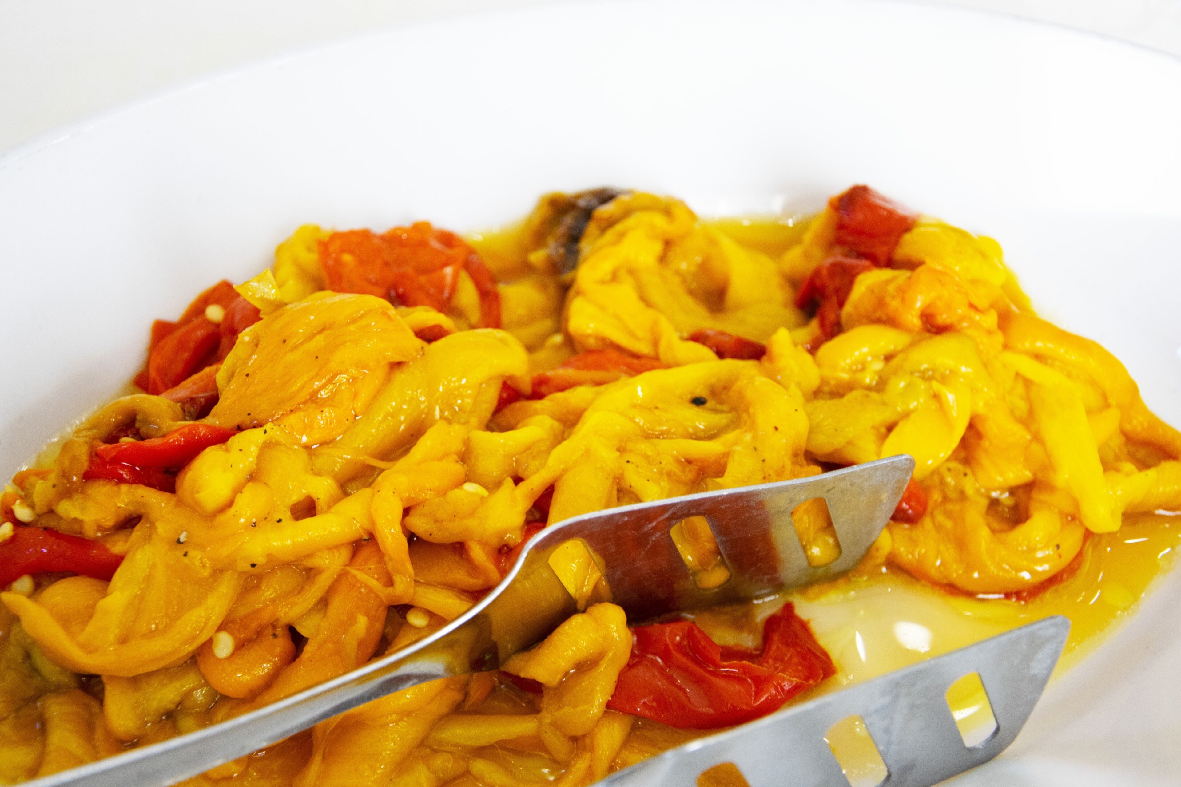 Un plato blanco con un guiso amarillo y rojo, posiblemente con verduras y carne, y un tenedor.