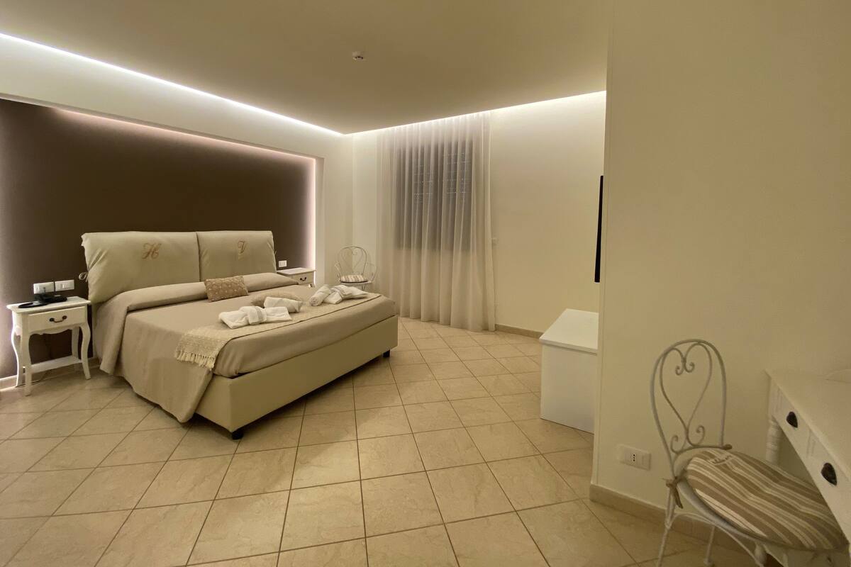 A bedroom with a bed, bedside tables, a chair, and a desk.