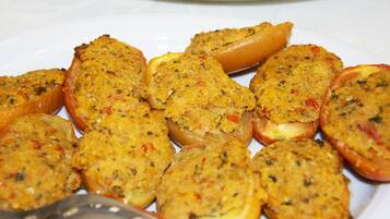 Une assiette de tomates farcies, recouvertes d’une croûte dorée, servies avec un quartier de citron.