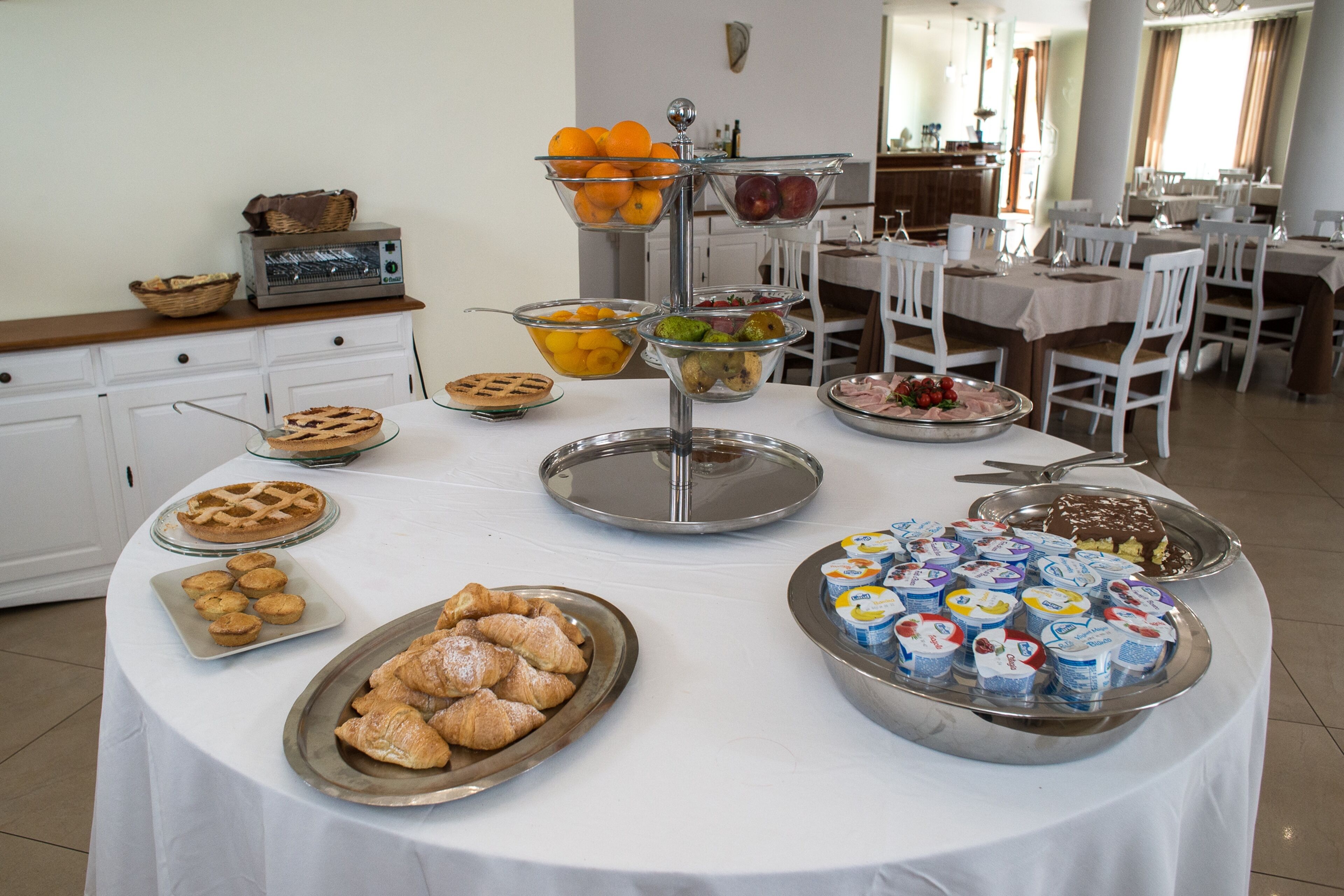 Taula de buffet amb diversos plats, com ara pastissos, fruita i copets de iogurt.
