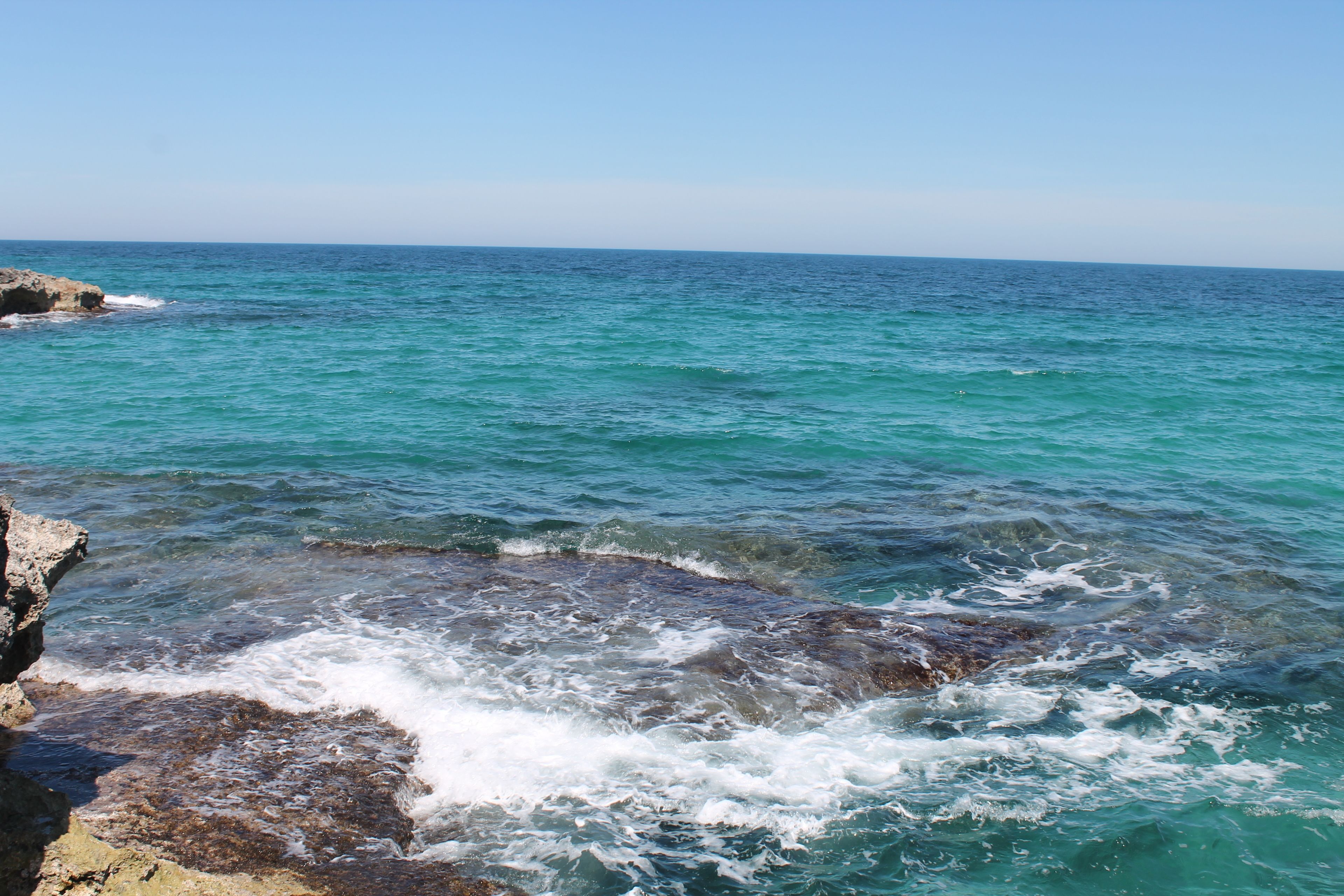 A coastal scene with clear turquoise water and rocky outcrops.