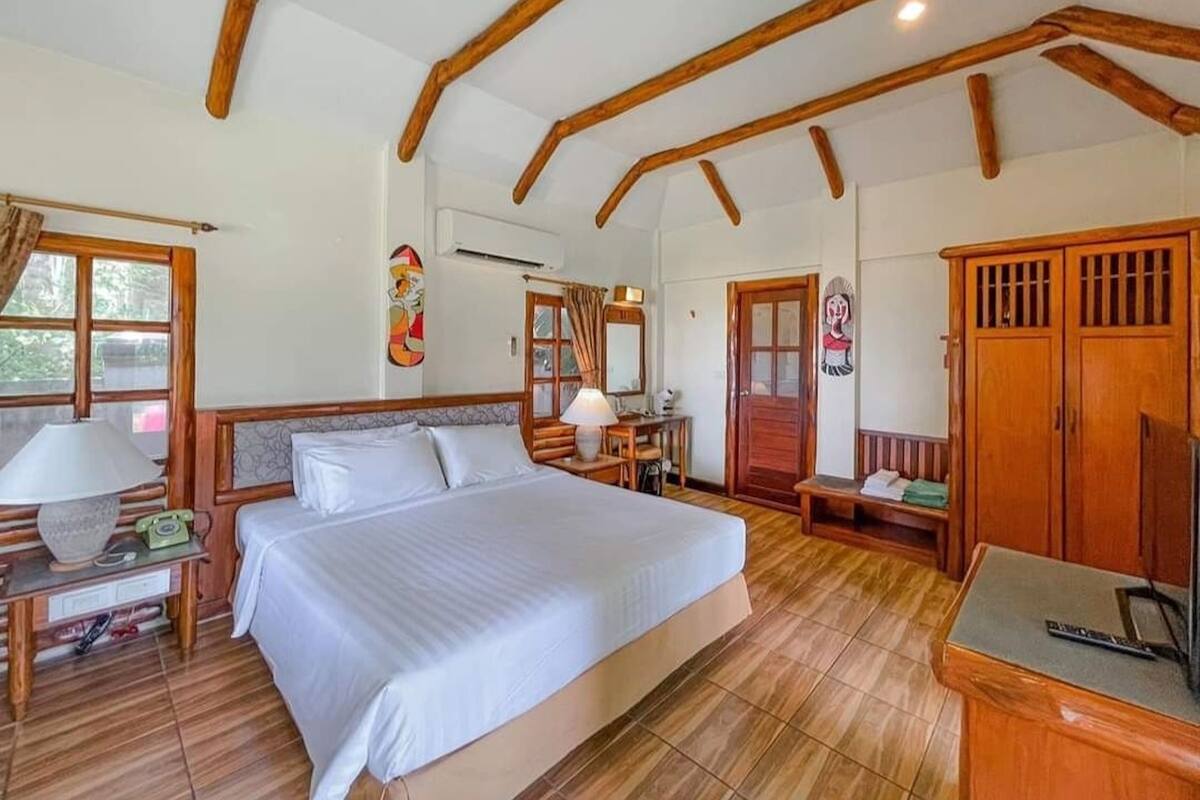Un dormitorio con una cama grande, vigas de madera, un escritorio y un armario.