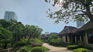 A traditional-style courtyard with a central pathway, surrounded by lush greenery and traditional buildings. - Botany Beach Resort Pattaya (Sattahip)