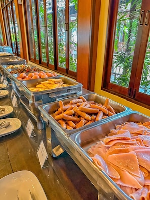 Un buffet proposant une variété de plats, notamment des viandes et des légumes coupés en tranches.